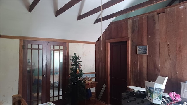 interior space featuring lofted ceiling with beams and wood walls