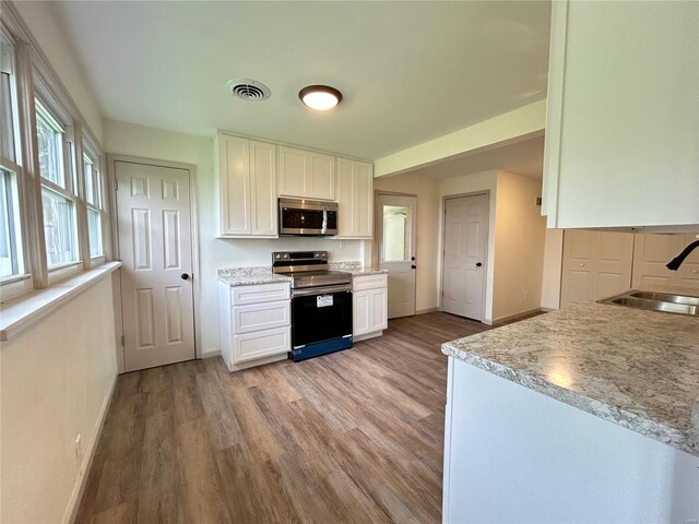 kitchen with white cabinetry, stainless steel appliances, sink, and light hardwood / wood-style floors