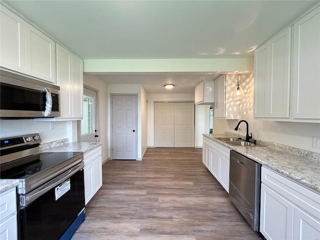 kitchen with light wood-type flooring, white cabinets, appliances with stainless steel finishes, and sink