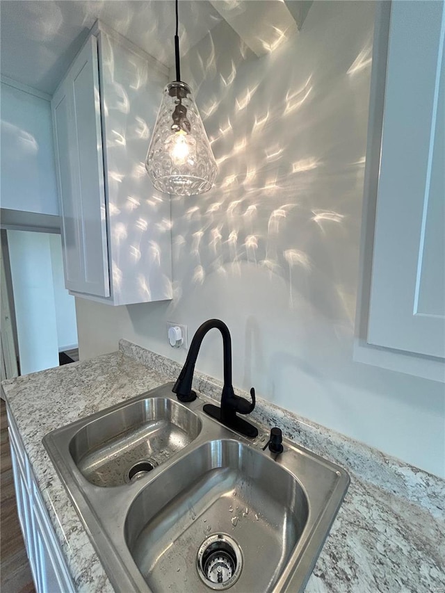 details featuring pendant lighting, white cabinetry, light stone counters, and sink