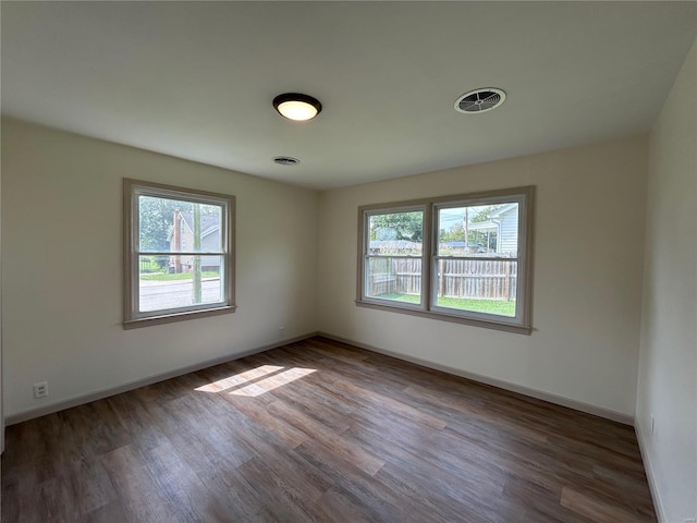 spare room with dark wood-type flooring and plenty of natural light