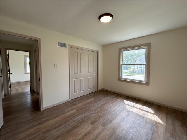 unfurnished bedroom featuring a closet and dark hardwood / wood-style flooring