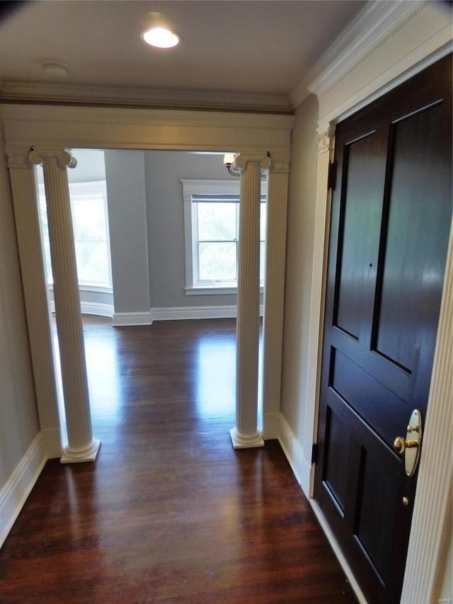 hall with ornamental molding, dark wood-type flooring, and decorative columns