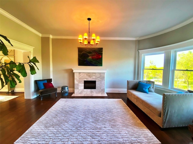 living room with a tiled fireplace, dark wood-type flooring, crown molding, and an inviting chandelier