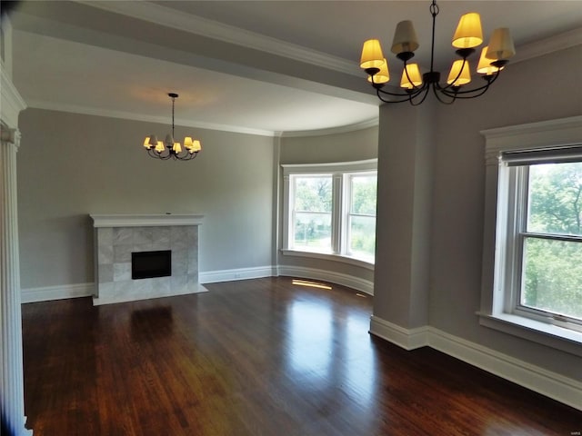 unfurnished living room with a tiled fireplace, dark hardwood / wood-style flooring, a notable chandelier, and ornamental molding