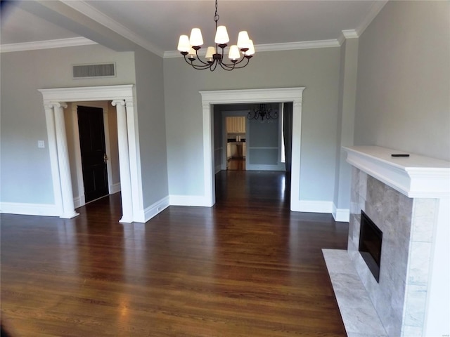 unfurnished living room with dark wood-type flooring, a fireplace, a notable chandelier, and ornamental molding