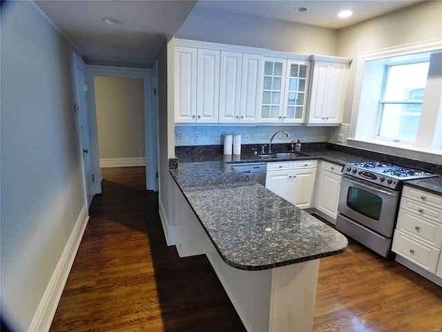 kitchen with white cabinets, appliances with stainless steel finishes, dark hardwood / wood-style flooring, sink, and kitchen peninsula