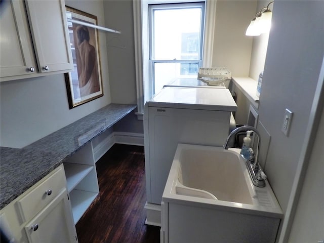 clothes washing area featuring washer and dryer, cabinets, dark hardwood / wood-style floors, and sink