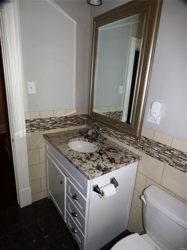 bathroom with tile walls, toilet, and vanity