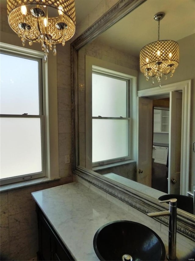 bathroom with a healthy amount of sunlight, a notable chandelier, and vanity