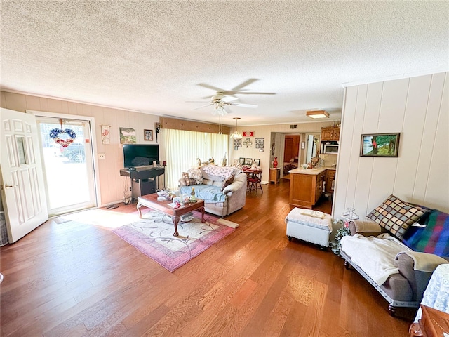 living room featuring ceiling fan, wood-type flooring, and a textured ceiling