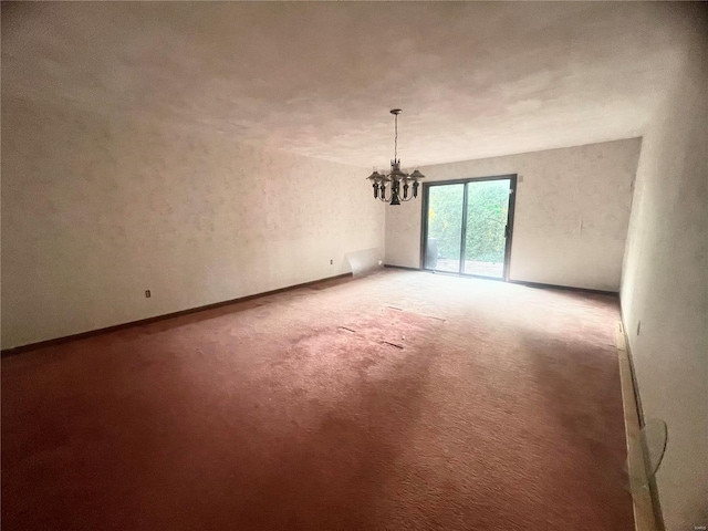 empty room featuring carpet flooring and a notable chandelier