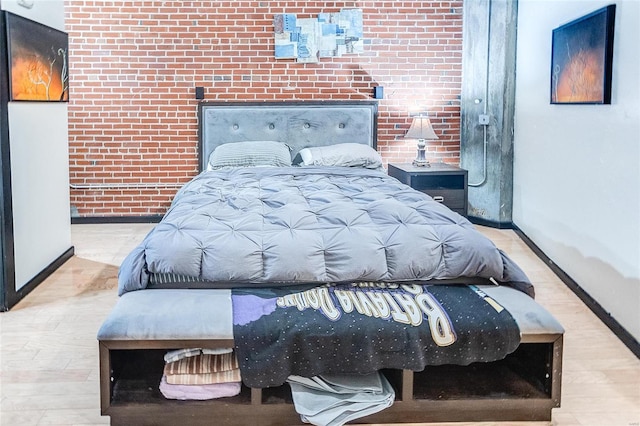 bedroom with brick wall and light hardwood / wood-style flooring