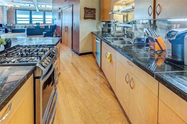 kitchen featuring a chandelier, stainless steel appliances, light brown cabinetry, sink, and light hardwood / wood-style floors