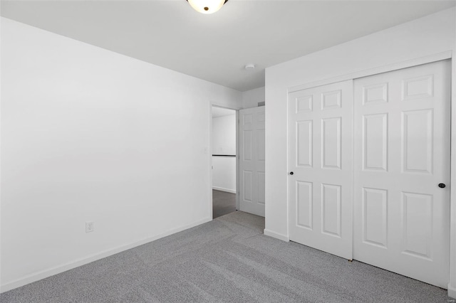 unfurnished bedroom with light colored carpet and a closet