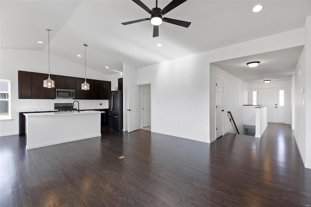 kitchen featuring ceiling fan, hanging light fixtures, dark wood-type flooring, lofted ceiling, and black fridge