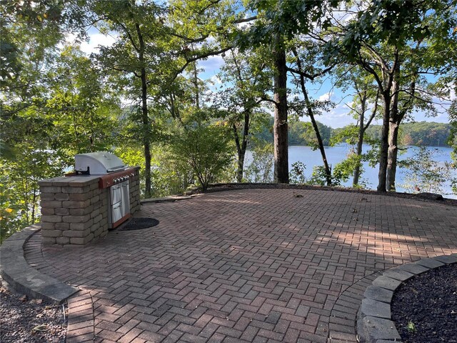 view of patio featuring exterior kitchen and a water view