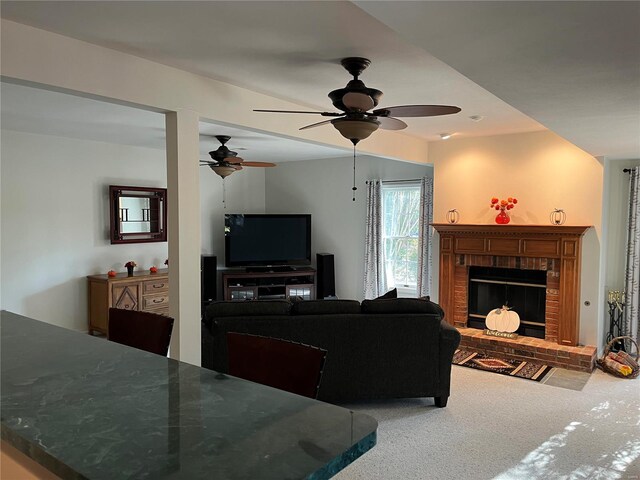 carpeted living room with a brick fireplace and ceiling fan