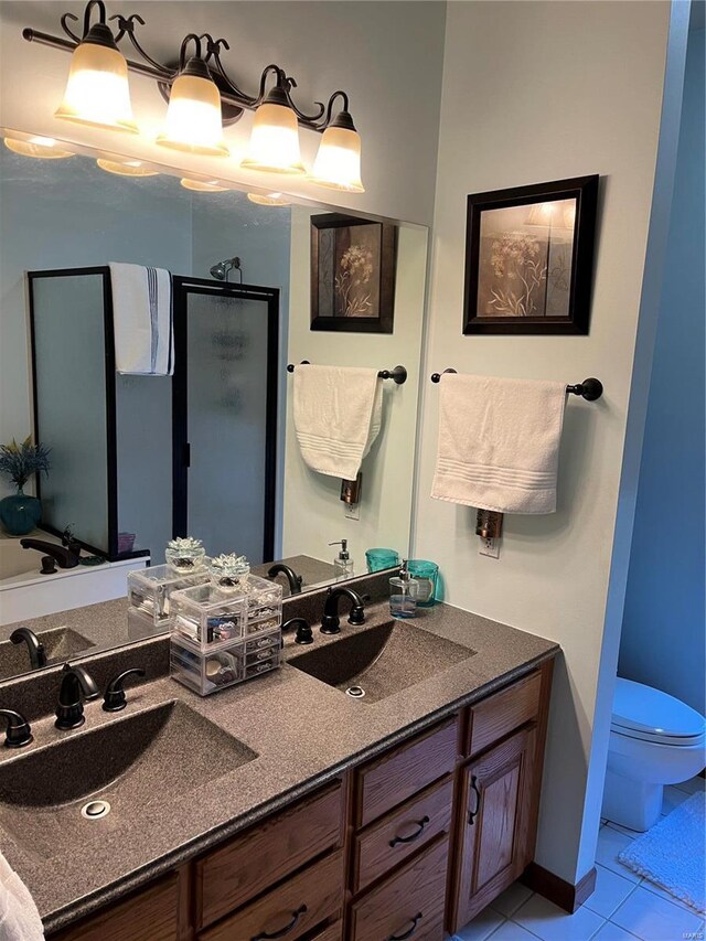 bathroom with tile patterned flooring, a shower with door, vanity, and toilet