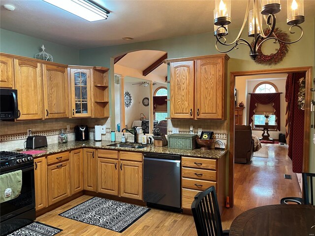 kitchen with dark stone counters, black appliances, and light hardwood / wood-style flooring