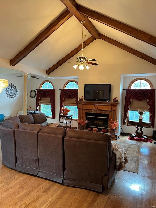 living room with light hardwood / wood-style floors, high vaulted ceiling, beam ceiling, and a healthy amount of sunlight