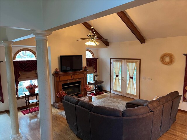 living room featuring a brick fireplace, light wood-type flooring, ceiling fan, french doors, and beam ceiling