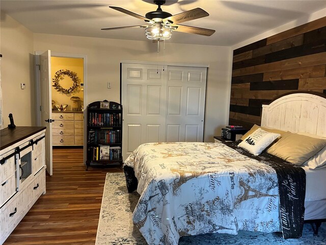 bedroom with ceiling fan, a closet, wood walls, and dark hardwood / wood-style flooring