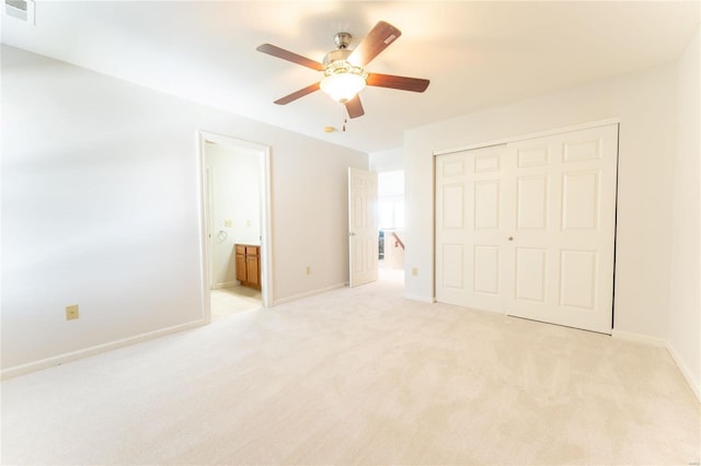 unfurnished bedroom featuring ceiling fan, light carpet, connected bathroom, and a closet