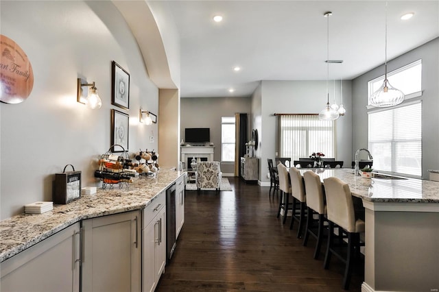 kitchen featuring a wealth of natural light, light stone counters, sink, and dark hardwood / wood-style floors