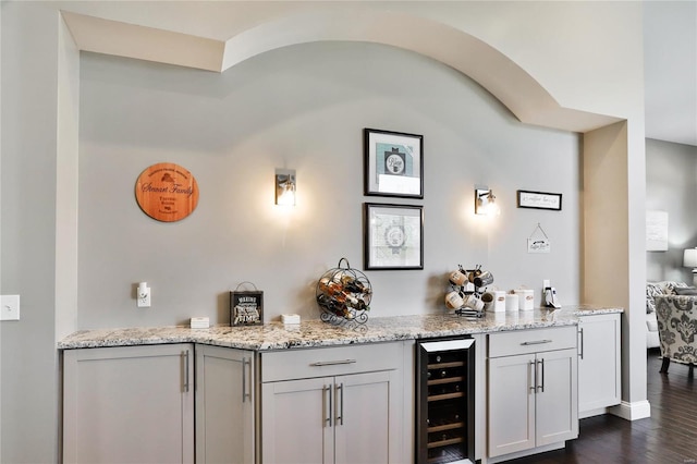 bar featuring dark wood-type flooring, light stone counters, beverage cooler, and white cabinets