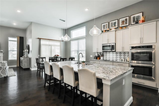 kitchen featuring dark hardwood / wood-style flooring, an island with sink, sink, appliances with stainless steel finishes, and white cabinets