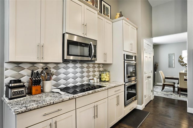 kitchen with dark wood-type flooring, stainless steel appliances, light stone counters, and tasteful backsplash