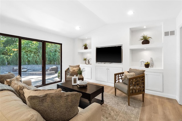 living room with built in shelves, light wood-type flooring, and lofted ceiling