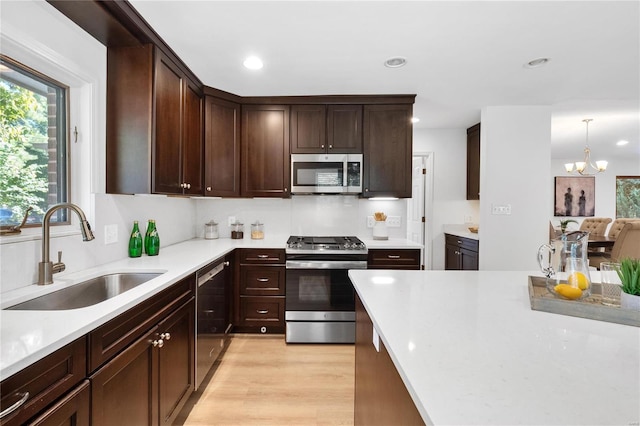 kitchen featuring light hardwood / wood-style flooring, a notable chandelier, hanging light fixtures, stainless steel appliances, and sink