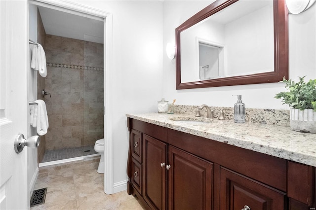 bathroom with toilet, a tile shower, and vanity