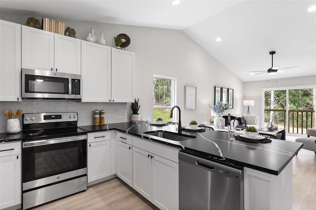 kitchen featuring light hardwood / wood-style flooring, stainless steel appliances, sink, kitchen peninsula, and white cabinetry