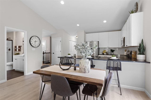 dining area featuring recessed lighting, vaulted ceiling, light wood-style flooring, and baseboards