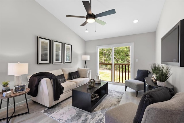 living room with ceiling fan, light hardwood / wood-style floors, and vaulted ceiling