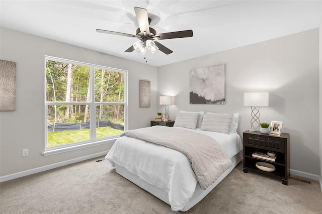 bedroom featuring multiple windows, ceiling fan, and light colored carpet