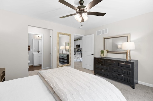 bedroom with light colored carpet, ceiling fan, and ensuite bathroom