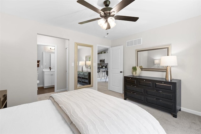 carpeted bedroom featuring baseboards, visible vents, a ceiling fan, ensuite bathroom, and a sink