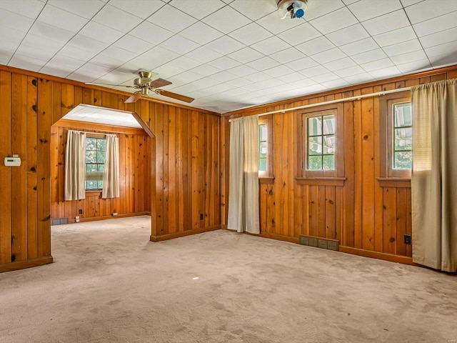 interior space featuring wood walls, ceiling fan, and a wealth of natural light