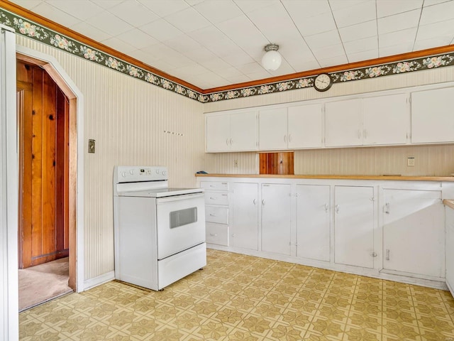 kitchen with white range with electric stovetop, wooden walls, and white cabinets