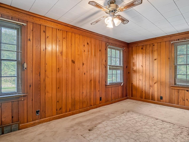 unfurnished room with carpet flooring, ceiling fan, and wooden walls