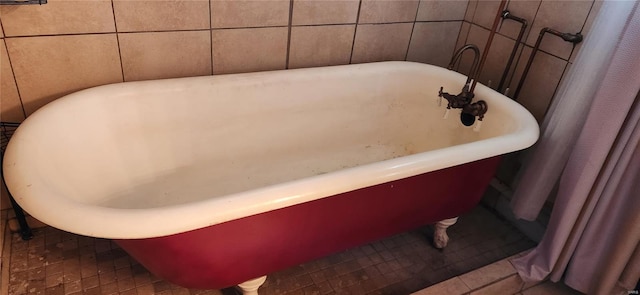 bathroom with a tub to relax in, tile walls, and tile patterned flooring