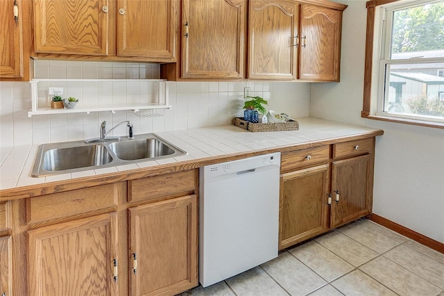 kitchen featuring white dishwasher, sink, light tile patterned floors, and tasteful backsplash