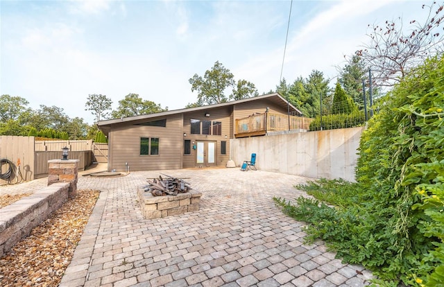 back of house featuring a fire pit, a patio, and a hot tub