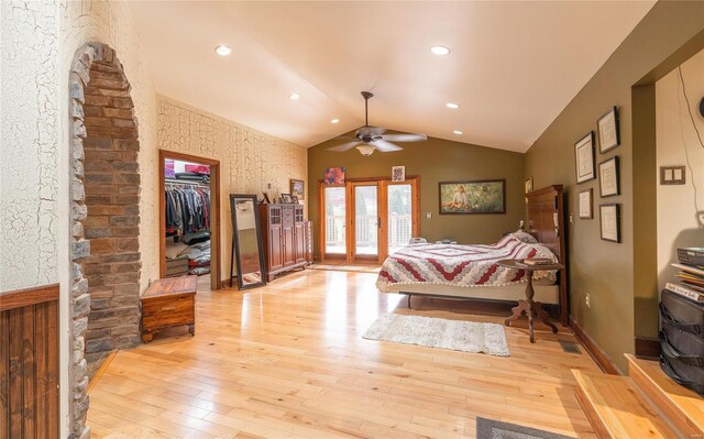 bedroom featuring light wood-type flooring, ceiling fan, a closet, lofted ceiling, and a walk in closet