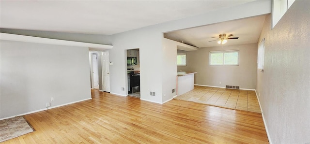 unfurnished living room featuring light wood-type flooring, vaulted ceiling, and ceiling fan