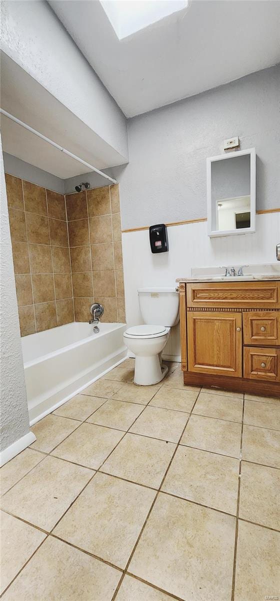 full bathroom with a skylight, tiled shower / bath, toilet, and vanity